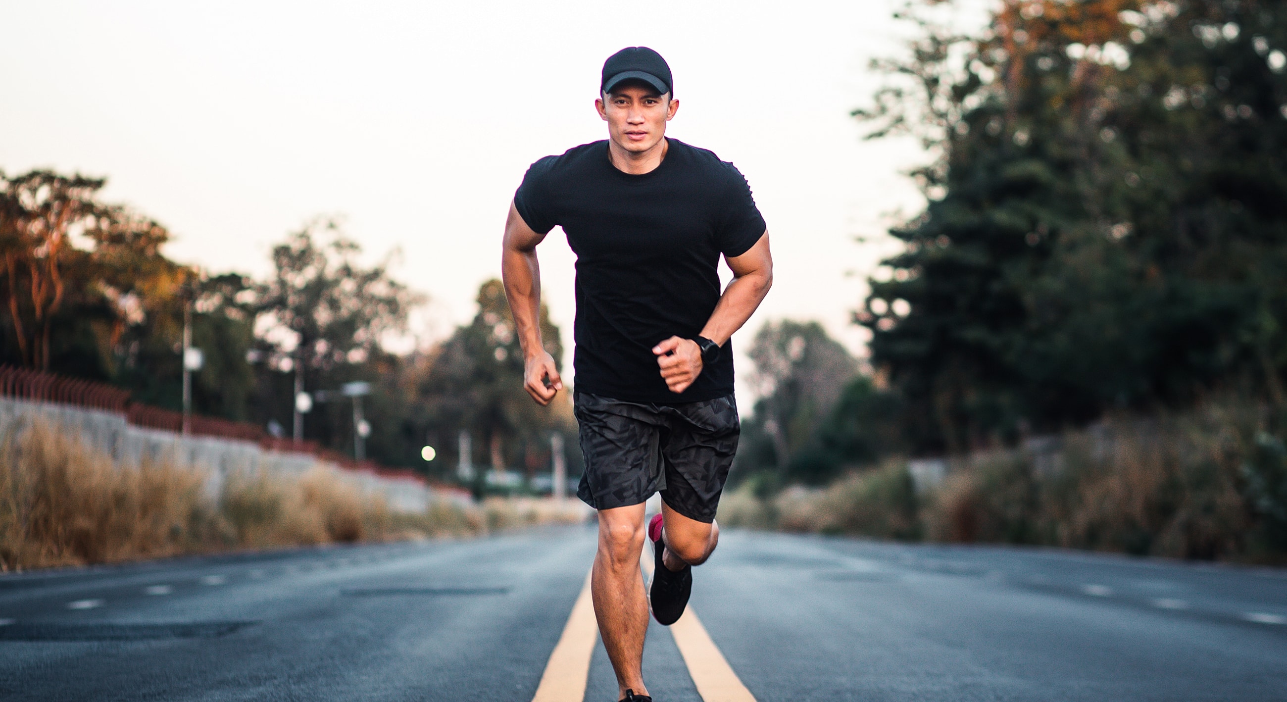 Man running on a deserted road at sunset.